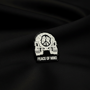 Pin with skull design and 'Peace of Mind' text on a black background
