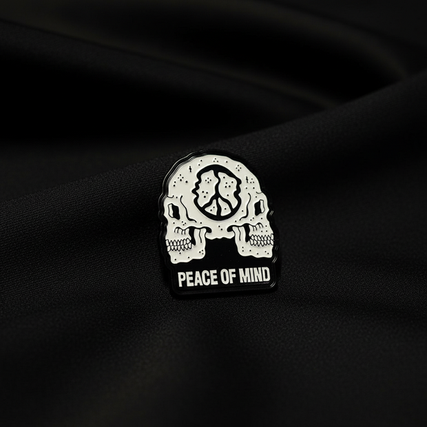 Pin with skull design and 'Peace of Mind' text on a black background