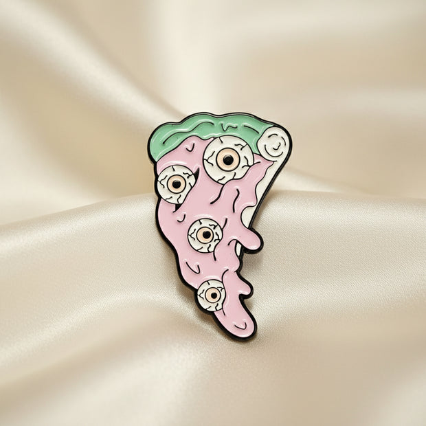 Enamel pin shaped like a slice of pink pizza on a light colored background.