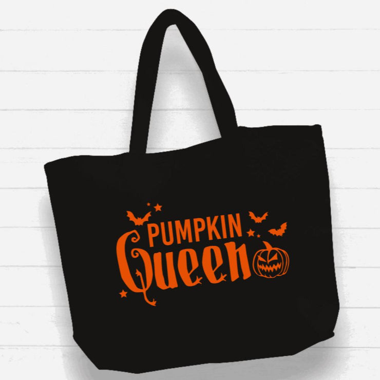 Black tote bag with 'Pumpkin Queen' text and pumpkin graphics on a white wooden background