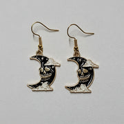 Moon-shaped earrings with black and gold design on a light gray background