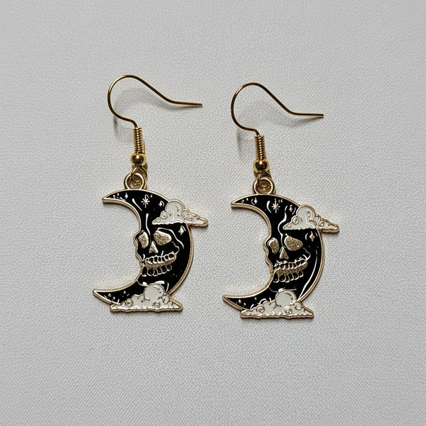 Moon-shaped earrings with black and gold design on a light gray background