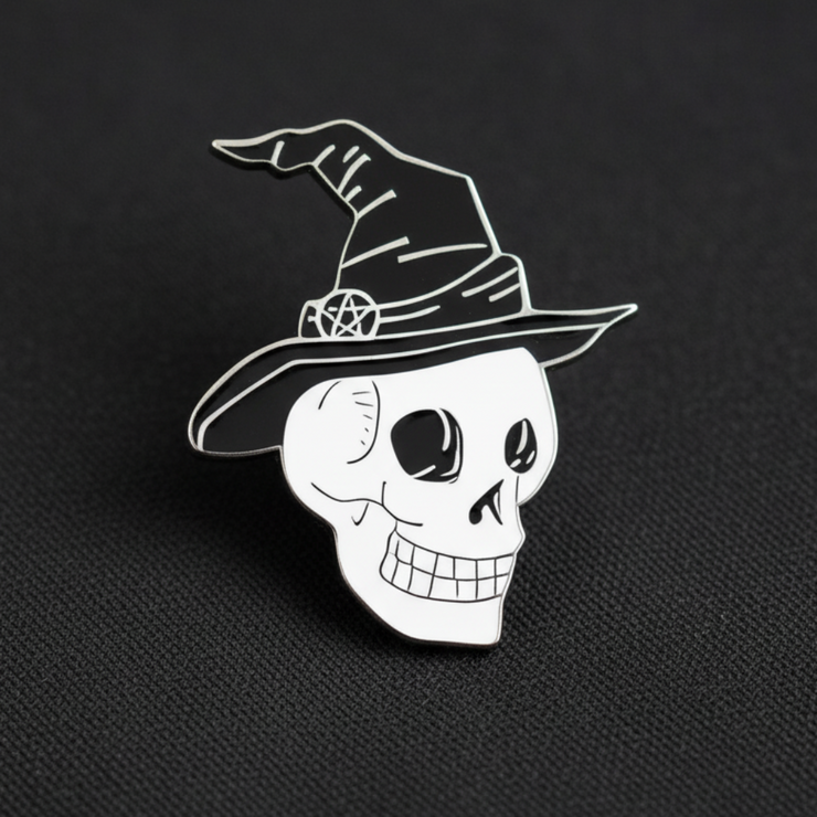 The Skull in Witch Hat Enamel Lapel Pin by Bleak Boutique features a cartoon-style skull with a pentacle-adorned witch hat on a gray textured background—an ideal spooky accessory for your collection.