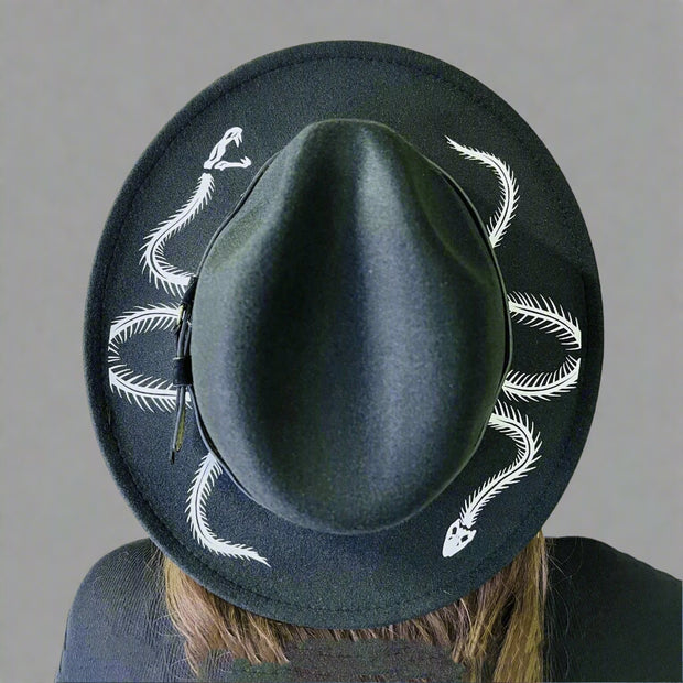 Black hat with white skeleton snake designs on a wooden surface