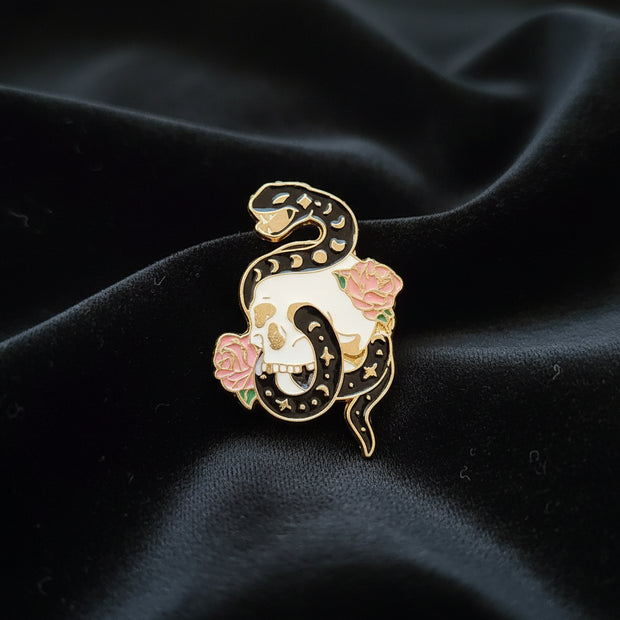 Decorative snake-shaped pin with floral details on a dark surface