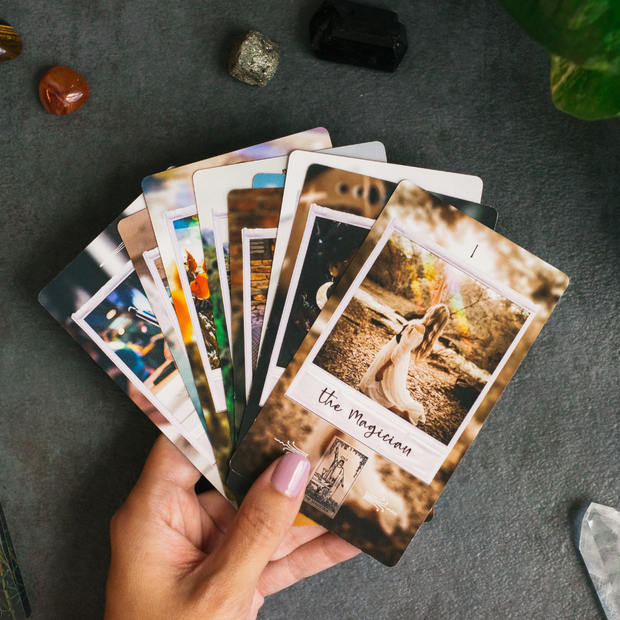 Hand holding tarot cards with a dark surface and crystals in the background