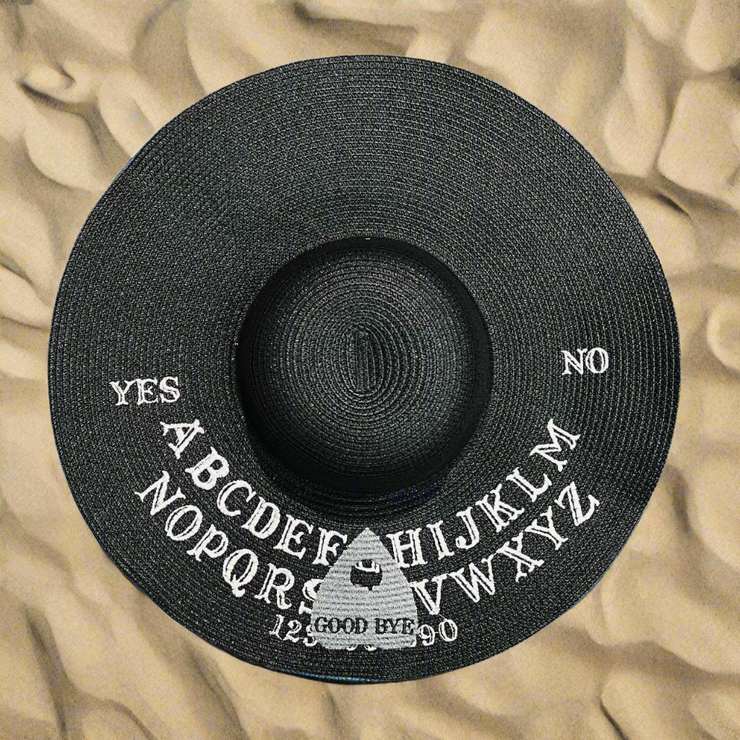 Black hat with Ouija spirit board design on a beach sand background