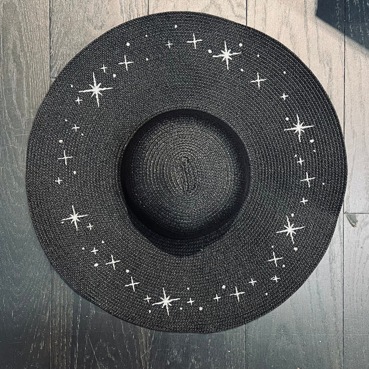 Black straw hat with star patterns on a wooden surface