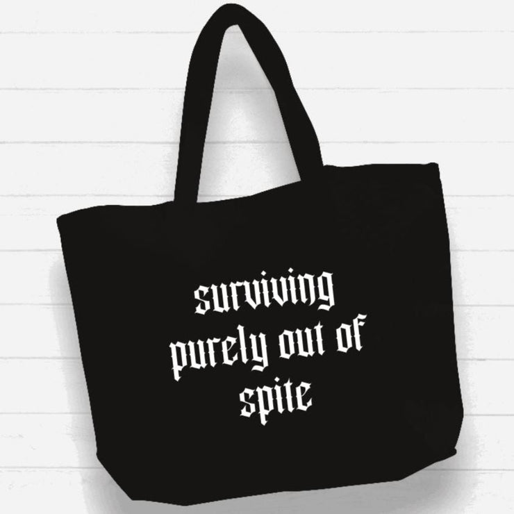 Black tote bag with white text on a light wooden background