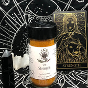 Tarot Card Spice Blend "Strength" by Dahlia's Enchanted Kitchen in front of the Strength tarot card.