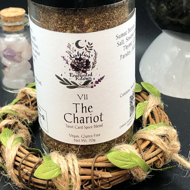 Spice jar labeled 'The Chariot' from Dahlia's Enchanted Kitchen on a dark surface with decorative elements.