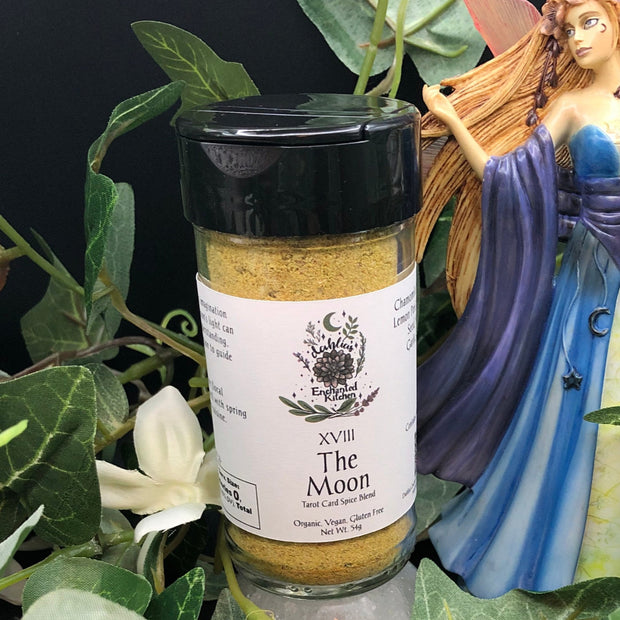 Tarot Card Spice Blend "The Moon" by Dahlia's Enchanted Kitchen surrounded by foliage and next to a fairy statue