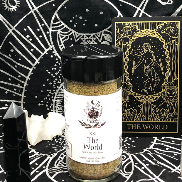 A jar of Tarot Card Spice Blend "The World" by Dahlia's Enchanted Kitchen surrounded by tarot themed items.