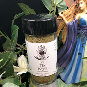 Tarot Card Spice Blend "The World" by Dahlia's Enchanted Kitchen with a fairy statue and greenery in the background.