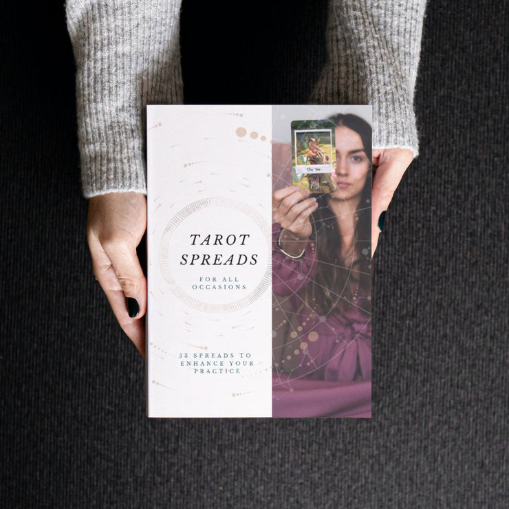 Book titled 'Tarot Spreads for All Occasions' held by a person wearing a gray sweater.