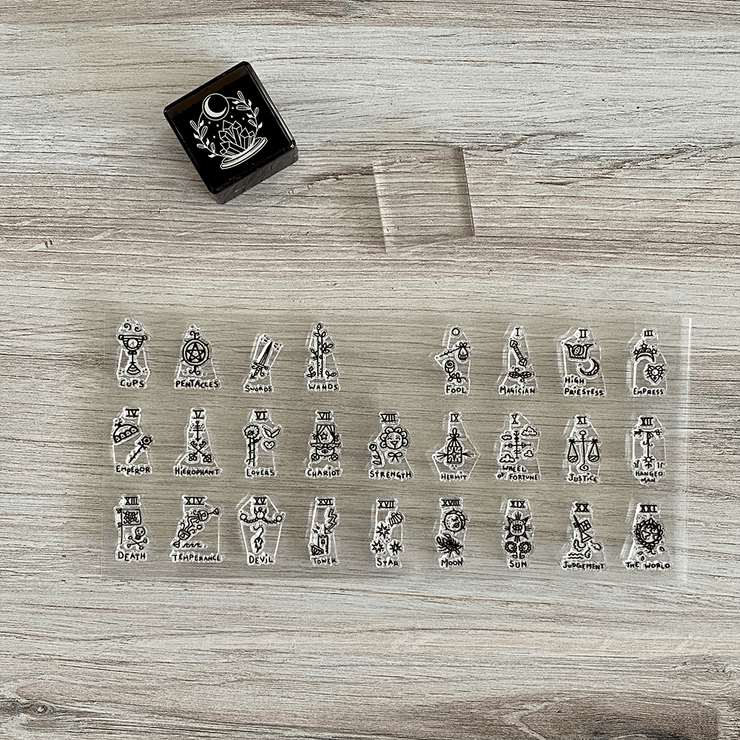 Set of tarot card suits on a clear acrylic sheet with a black box on a wooden surface.