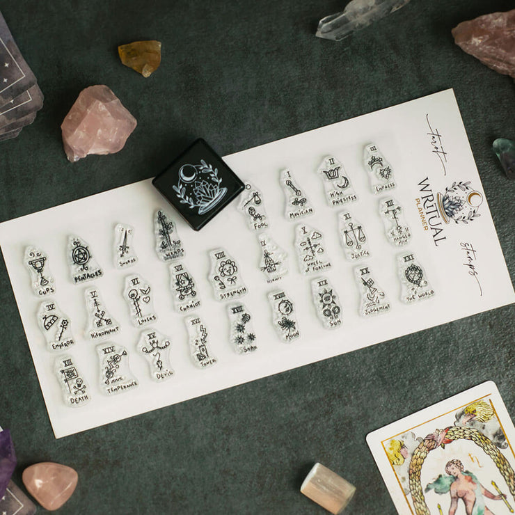 Sheet of tarot card symbols with a tarot card and crystals on a dark surface