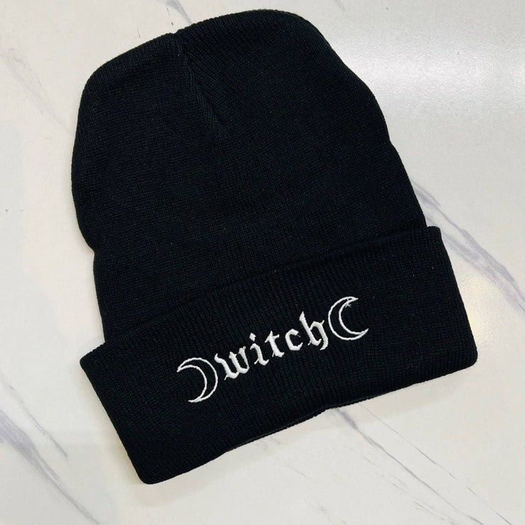 Black beanie with 'witch' embroidered on a white background