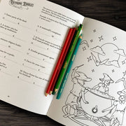 Open book with coloring page and pencils on a wooden surface