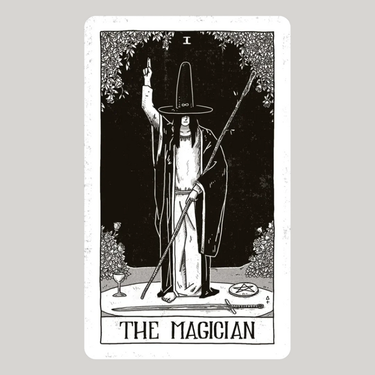 The Magician card of the Black Ritual Tarot. The card depicts a figure standing at a table with various tools laid out before him, symbolizing the elements of earth, air, fire, and water. He raises one hand toward the sky and points the other to the ground, indicating the connection between the spiritual and the material realms.