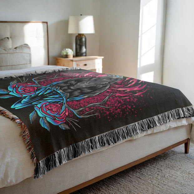 Intriguing Crow and Flowers Woven Throw Blanket with a crow in shades of black and blue against a dramatic background of magenta splashes and abstract shapes. Perfect for wall decoration, a cozy throw, or a unique picnic spread.