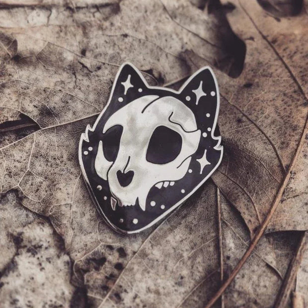 Intricately designed Gothic Cat Skull Enamel Lapel Pin featuring a high gloss silver chrome finish, with the cat's face and ears outlined in striking black enamel and gloss silver star accents.