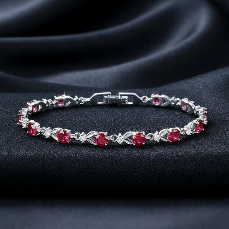 Silver bracelet with red gemstones on a dark fabric background