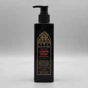 Black bottle of liquid soap with gold text on a metallic surface