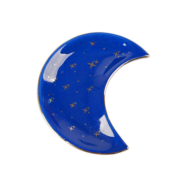 The Bleak Boutique Crescent Moon Ceramic Jewelry Valet Dish features a blue glaze with gold star accents, displayed on a white background—ideal for holding jewelry or small trinkets.