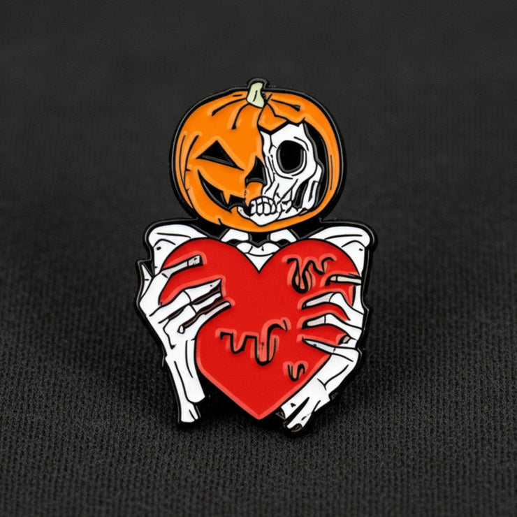 This enamel lapel pin features a spooky skeleton with a jack-o-lantern head, extending a heart in a gesture both eerie and endearing.
